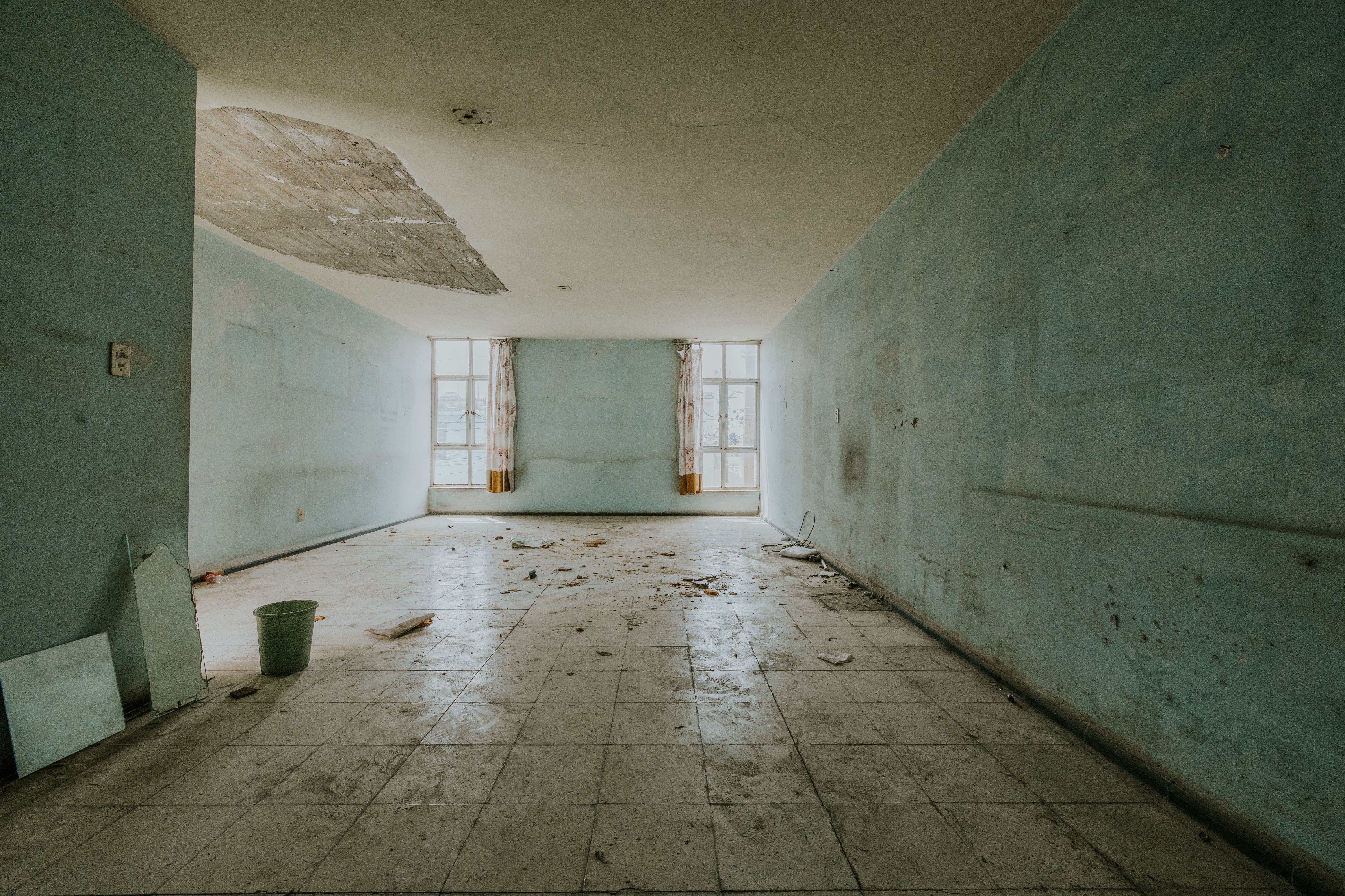 A ground-floor wall with a horizontal damp tide mark and peeling paint about a metre above the floor
